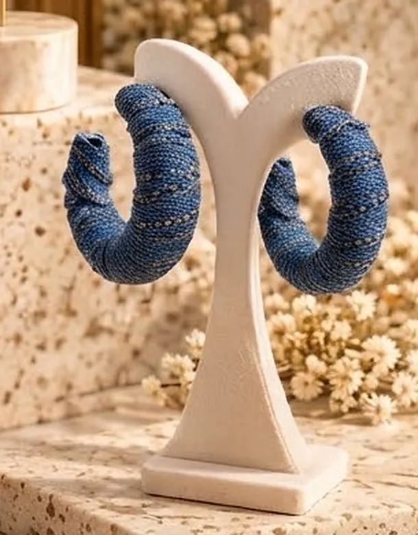 Denim-wrapped hoop earrings on a cream stand